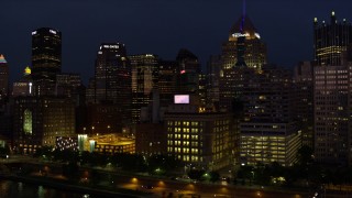 4K aerial stock footage flying by skyscrapers and tilt down on Byham Theater, Downtown Pittsburgh, night Aerial Stock Footage | AX108_171