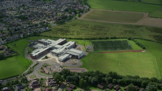 AX109_054E - 5.5K aerial stock footage of orbiting Wallace High School and soccer field, Stirling, Scotland