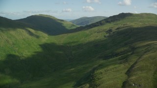 AX110_092E - 5.5K aerial stock footage of flying toward lush green mountains, Scottish Highlands, Scotland