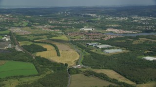 AX110_226E - 5.5K aerial stock footage of lakefront homes and farm fields, Broadwood Loch, Scotland