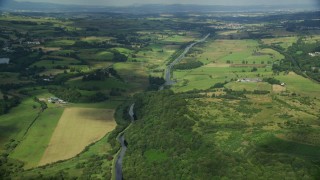 AX110_229E - 5.5K aerial stock footage of farm fields around a river, Cumbernauld, Scotland