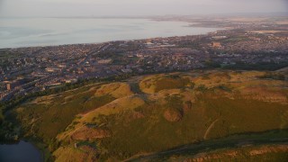 AX112_088E - 5.5K aerial stock footage approach residential neighborhoods from Arthur's Seat, Edinburgh Scotland at sunset