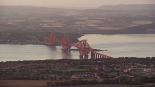 AX112_120E - 5.5K aerial stock footage of Forth Bridge spanning Firth of Forth, Edinburgh, Scotland at sunset