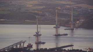 AX112_124E - 5.5K aerial stock footage of passing a bridge under construction, Edinburgh, Scotland at sunset