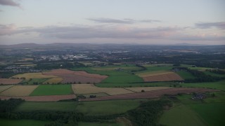 5.5K aerial stock footage of passing by farm fields at sunset in Broxburn, Scotland Aerial Stock Footage | AX112_131E