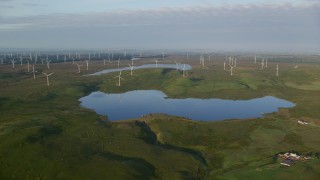 AX113_010E - 5.5K aerial stock footage approach Lochgoin Reservoir and windmills, Eaglesham, Scotland at sunrise