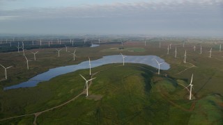 AX113_013E - 5.5K aerial stock footage pan across windmills and reservoir, Eaglesham, Scotland at sunrise