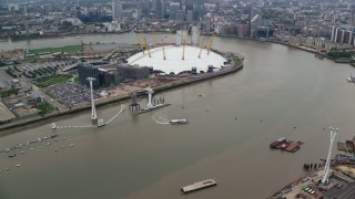 AX114_145E - 5.5K aerial stock footage fly over O2 arena, approach Canary Wharf skyscrapers, London, England