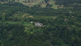 5.5K aerial stock footage of approach and title down on a large rural home among the trees, Redhill, England Aerial Stock Footage | AX114_384