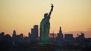 AX118_042E - 5.5K aerial stock footage orbit back of the Statue of Liberty at sunrise, New York