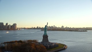 5.5K aerial stock footage of flying away from the Statue of Liberty at sunrise in New York Aerial Stock Footage | AX118_118