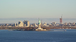 5.5K aerial stock footage of flying by Statue of Liberty at sunrise in New York Aerial Stock Footage | AX118_139