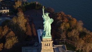 AX118_144E - 5.5K aerial stock footage approach and tilt to bird's eye of the Statue of Liberty at sunrise in New York