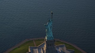 5.5K aerial stock footage of flying away from the Statue of Liberty at sunrise in New York Aerial Stock Footage | AX118_148