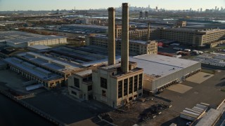 AX118_228 - 5.5K aerial stock footage of orbiting a riverfront factory at sunrise in Kearny, New Jersey