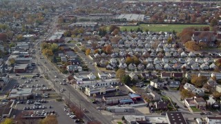 AX120_035E - 5.5K aerial stock footage of suburbs, sports fields and stores along a busy street in Autumn, Elmont, New York