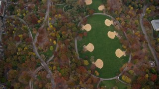 AX120_197 - 5.5K aerial stock footage of bird's eye of a theater and baseball diamonds in Central Park in Autumn, New York City