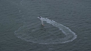 5.5K aerial stock footage of a harbor police boat speeding away from sailboat in New York Harbor at twilight Aerial Stock Footage | AX121_015