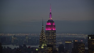 AX121_121 - 5.5K aerial stock footage of tops of the Empire State and Chrysler Buildings at twilight in Midtown, New York City