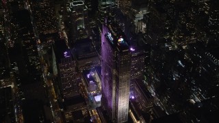 AX122_202E - 5.5K aerial stock footage of circling around Rockefeller Center with ice rink at Night in Midtown, NYC