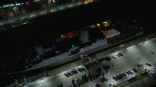 AX123_007E - 5.5K aerial stock footage orbit and tilt to bird's eye of a Naval Warship at Hell's Kitchen docks at Night in Midtown, NYC