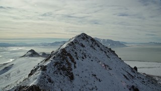 5.5K aerial stock footage fly over snowy Antelope Island ridge and peak toward Great Salt Lake in winter, Utah Aerial Stock Footage | AX125_048E