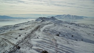 5.5K aerial stock footage fly over snowy ground toward wintery mountains, Antelope Island, Utah Aerial Stock Footage | AX125_090E