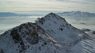 5.5K aerial stock footage approach and fly over snowy peak near shore of Great Salt Lake, Antelope Island, Utah Aerial Stock Footage | AX125_096E