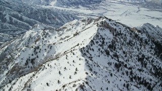 5.5K aerial stock footage of following a snowy mountain ridge dotted with evergreens in winter, Oquirrh Mountains, Utah Aerial Stock Footage | AX125_148E