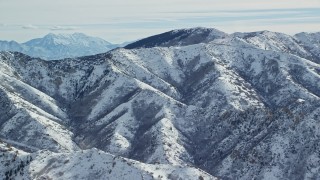 AX125_163 - 5.5K aerial stock footage of Oquirrh Mountains slopes with light snow in wintertime Utah