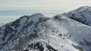 AX125_187 - 5.5K aerial stock footage slowly approach snowdrifts from a peak in the Oquirrh Mountains, Utah