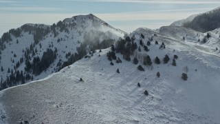 5.5K aerial stock footage of snowdrifts blowing from slope in the Oquirrh Mountains, Utah Aerial Stock Footage | AX125_190E