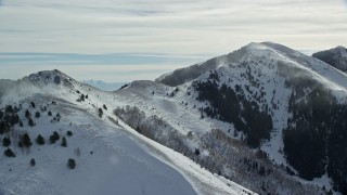 AX125_192 - 5.5K aerial stock footage of two peaks with snowdrifts in the Oquirrh Mountains or Utah in winter