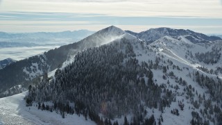 5.5K aerial stock footage of snowdrifts pluming from a mountain peak in wintertime in Utah's Oquirrh Mountains Aerial Stock Footage | AX125_199E