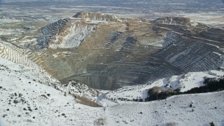 5.5K aerial stock footage approach Bingham Canyon Mine beyond snowy mountain ridge in winter, Utah Aerial Stock Footage | AX125_226E