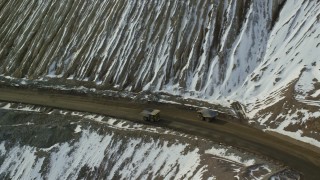 5.5K aerial stock footage of four gravel haulers at the Bingham Canyon Copper Mine with winter snow in Utah Aerial Stock Footage | AX125_248