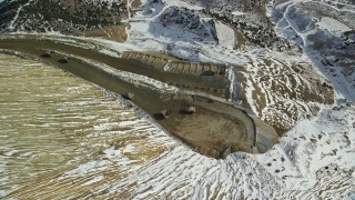 5.5K aerial stock footage of gravel haulers moving on dirt road at Bingham Canyon Mine with snow, Utah Aerial Stock Footage | AX125_253