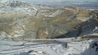 5.5K aerial stock footage fly over snowy mountain ridge to reveal enormous open pit copper mine with winter snow, Utah Aerial Stock Footage | AX125_260E