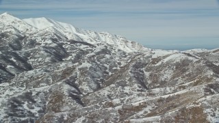 5.5K aerial stock footage of flying by mountains with light snow near larger white peaks in winter, Oquirrh Mountains, Utah Aerial Stock Footage | AX125_284E