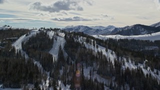 AX126_133 - 5.5K aerial stock footage orbit snowy mountains with ski runs and lifts at Deer Valley in winter, Utah