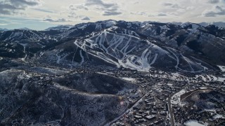 5.5K aerial stock footage of ski runs on a snowy mountain slope overlooking small town in winter, Park City, Utah Aerial Stock Footage | AX126_151