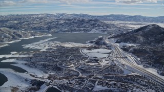 5.5K aerial stock footage approach condos and highway near the shore of Jordanelle reservoir with winter snow, Heber City, Utah Aerial Stock Footage | AX126_177E