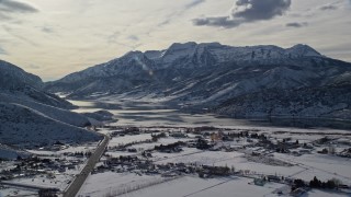 AX126_220E - 5.5K aerial stock footage approach frozen shore of Deer Creek Reservoir and mountains in winter, Heber City, Utah