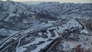 AX127_051E - 5.5K aerial stock footage approach I-80 through a frozen mountain pass in winter at sunset, Utah