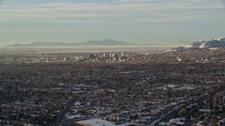 5.5K aerial stock footage of a view of Downtown Salt Lake City across suburban neighborhoods in winter at sunset, Utah Aerial Stock Footage | AX127_075