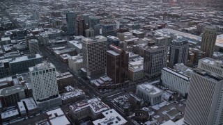 AX127_166 - 5.5K aerial stock footage orbit office buildings in Downtown Salt Lake City at sunset with winter snow, Utah