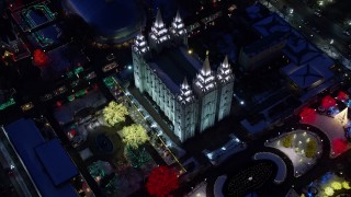 AX128_081E - 5.5K aerial stock footage bird's eye orbit of Salt Lake Temple with colorfully lit trees with winter snow at night, Downtown SLC, Utah