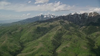 AX130_058E - 5.5K aerial stock footage of approaching green ridges, snowy peaks, Oquirrh Mountains, Utah