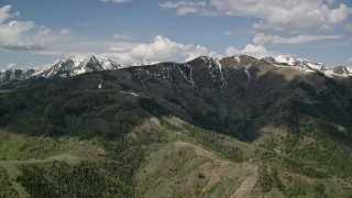 5.5K aerial stock footage of flying by snowy peaks, green ridges, Oquirrh Mountains, Utah Aerial Stock Footage | AX130_060E