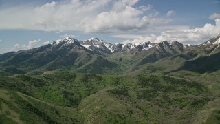 5.5K aerial stock footage of flying by snowy peaks, green ridges, Oquirrh Mountains, Utah Aerial Stock Footage | AX130_065E